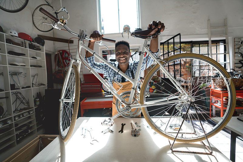 一家自行车作坊的黑人企业主看着照相机微笑着