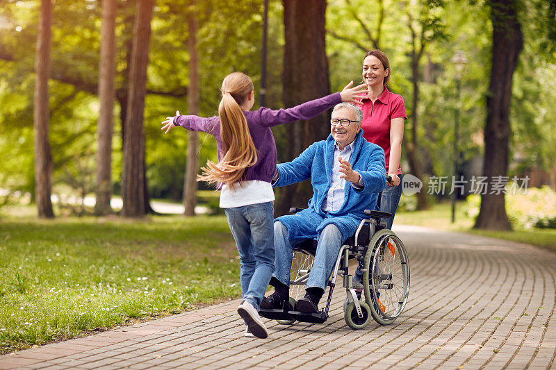 坐在轮椅上的快乐的残疾祖父欢迎他的孙女