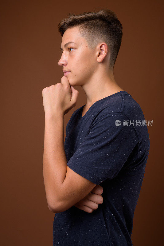工作室拍摄的年轻英俊的十几岁的男孩穿着蓝色的衬衫，以彩色的背景