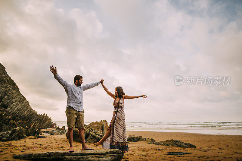 年轻夫妇在海滩上举起手臂