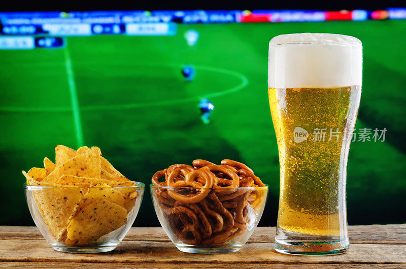 一边喝着啤酒，一边吃着零食，一边看球赛