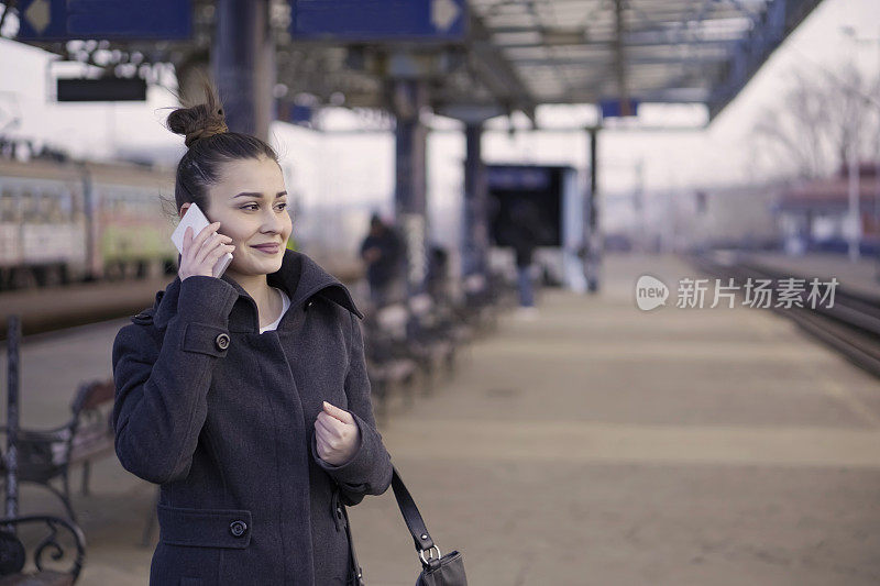 一个年轻女子在火车站用智能手机