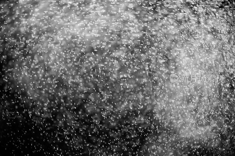 抽象的飞溅和纹理的白色水，雨或雪在黑暗的背景。