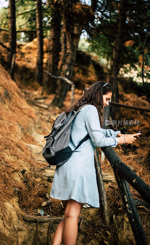一位女性徒步旅行者喜欢森林和一部手机