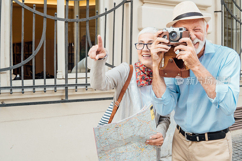 女人拿着地图站在丈夫旁边用相机拍照