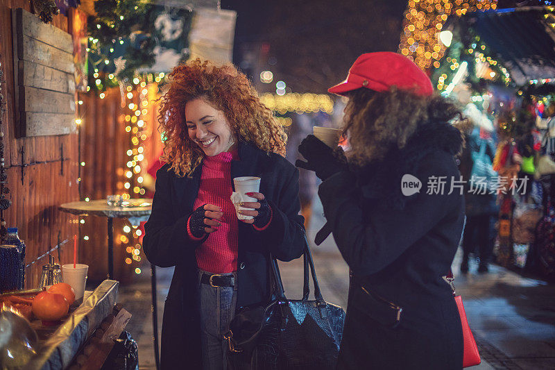 年轻漂亮的女人正在圣诞市场买热饮