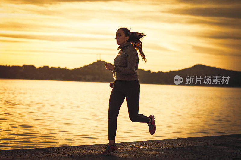 日落时分在海边跑步的女人