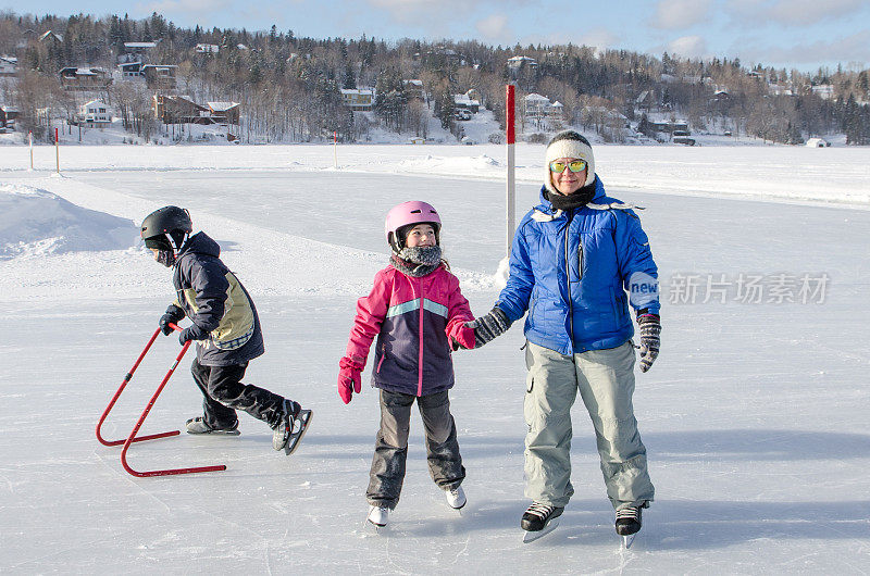 冬天，母亲和孩子们在博波特湖镇的溜冰场上滑冰