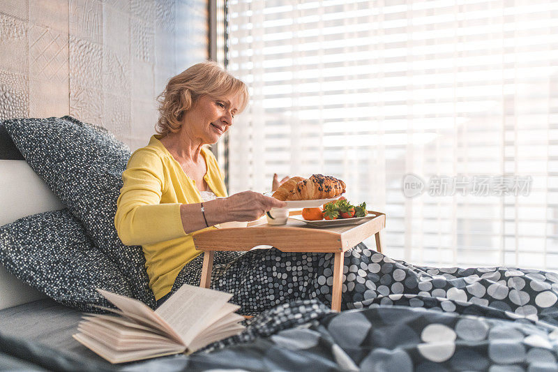 老女人在家里的床上吃早餐