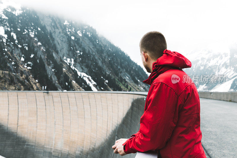 一个人站在大坝上看着齐勒塔尔阿尔卑斯山