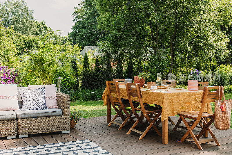 铺着橙色台布的餐桌矗立在绿色花园的木质露台上，为游园会准备