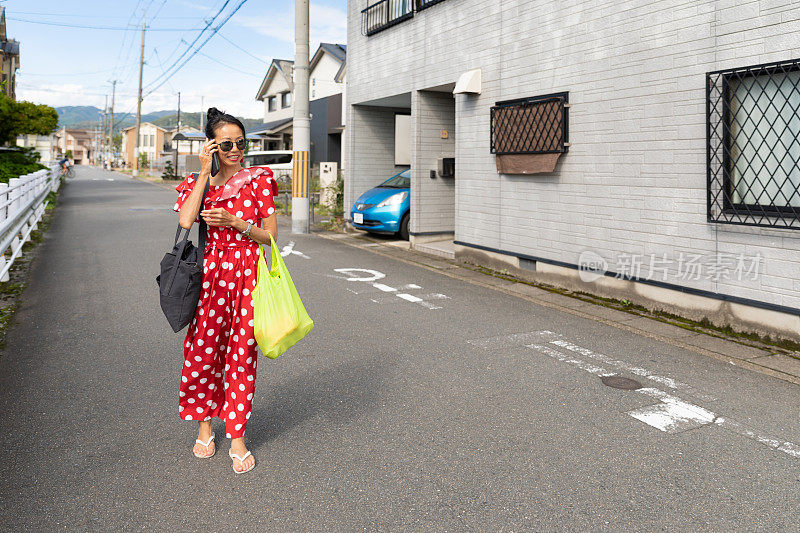 一个女人带着可重复使用的购物袋走在街上