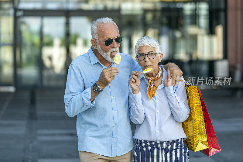 一对活跃的老年夫妇在购物中心购物成功后享用冰淇淋