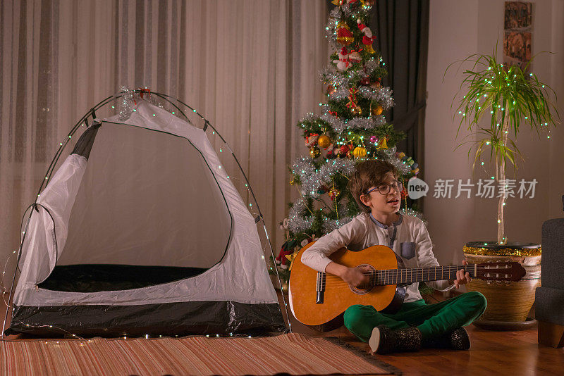 一个快乐的男孩弹着吉他庆祝圣诞节的肖像。