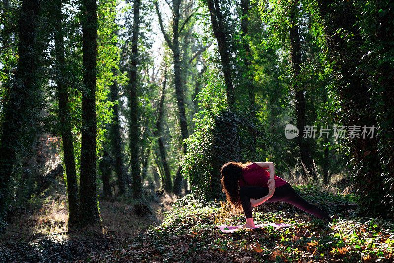 成年妇女在丛林中做瑜伽练习的照片