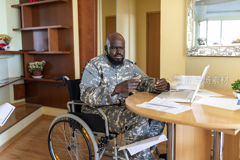 残废的美国海军陆战队员坐在轮椅上。忧心忡忡的轮椅上的非洲老兵正在关注家庭的财务法案