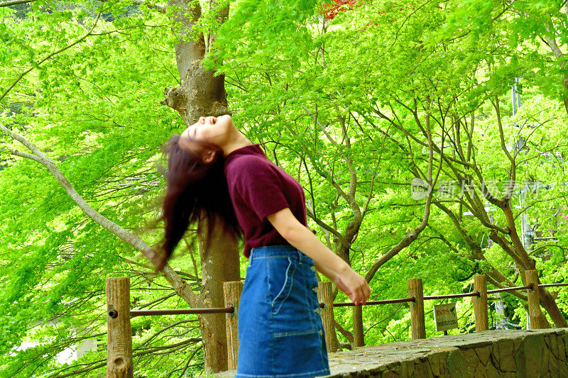 年轻的日本女人在新鲜的枫树叶下旋转她的长发