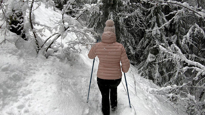 女性徒步旅行者沿着雪道行走