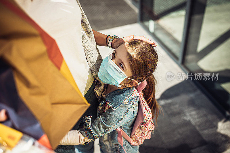 带着女儿戴着防护面具购物的女人