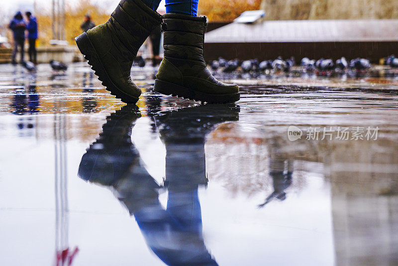 脚在胶靴雨水坑城市