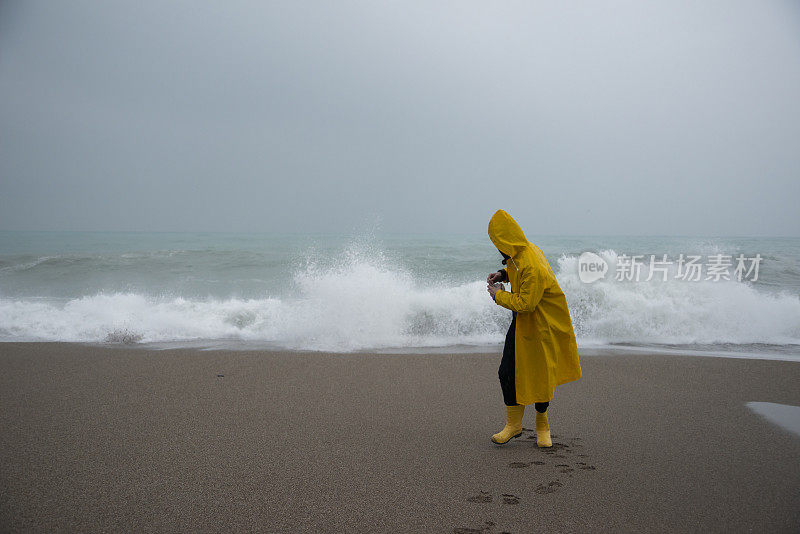 海滩上的风暴和穿着黄色雨衣的男人。暴风雨，暴雨，海岸，大浪