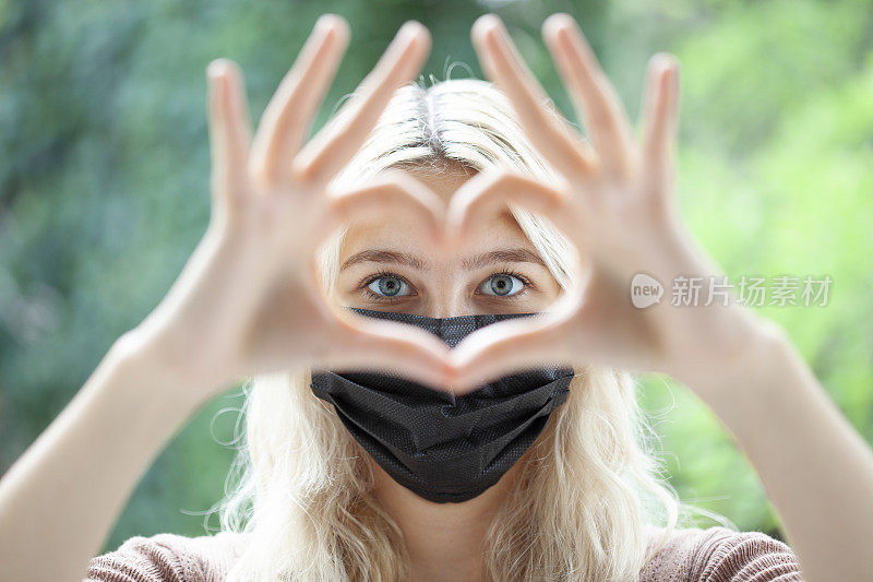 戴黑面具的女人做心脏手势抵御病毒
