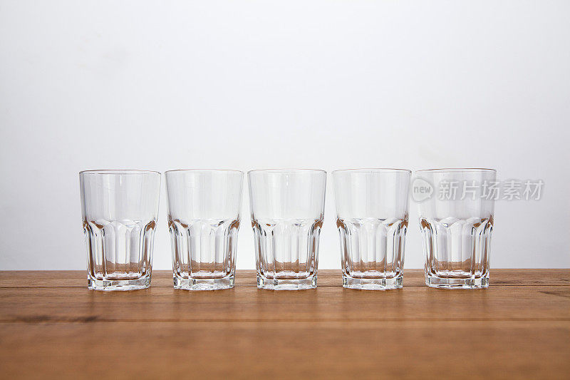 在一张木桌上，五个空的水杯排成一行，用复印空间直接观察