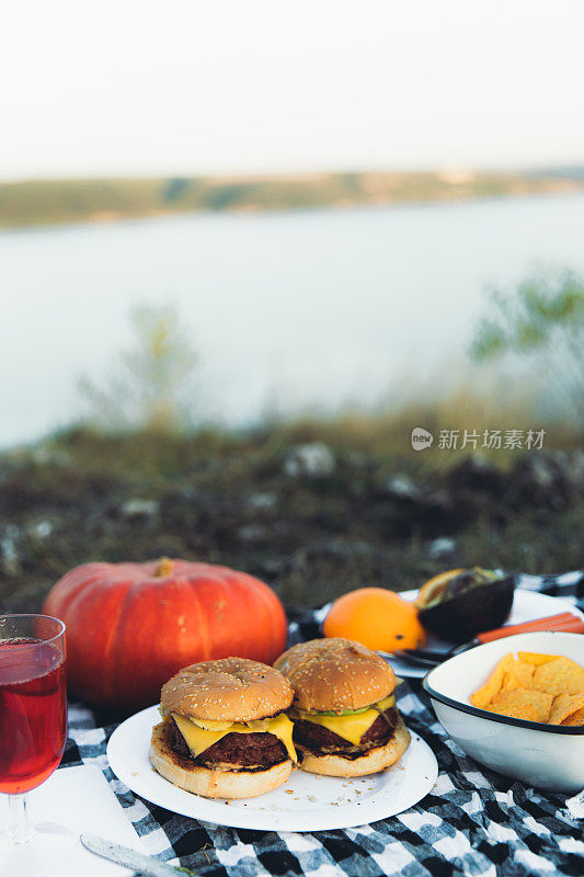 秋天在湖边野餐-在烤架上制作鳄梨酱汉堡