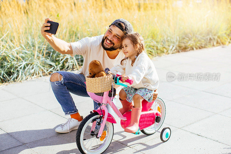 快乐的家庭，父亲教女儿在公园里骑自行车