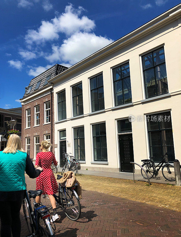 荷兰小镇的两名妇女在骑自行车(弗里斯兰斯克)