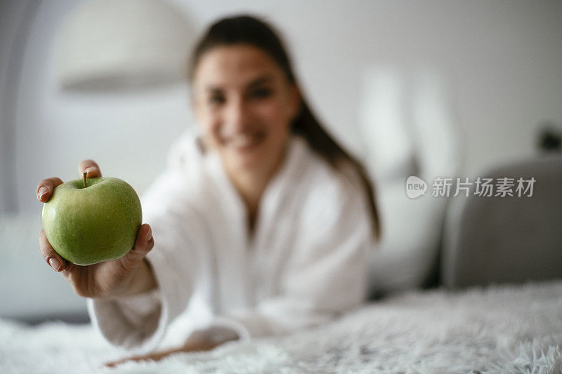 漂亮的女孩正在吃新鲜的苹果。