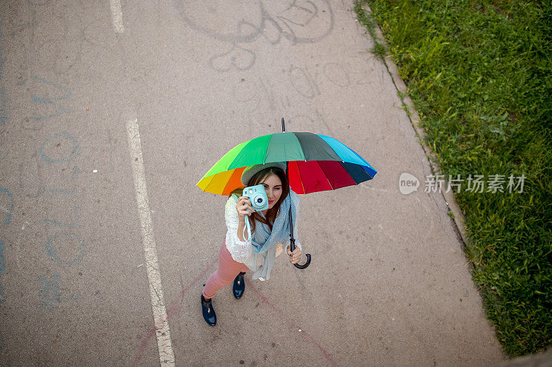 漂亮凉爽的女人带着五颜六色的雨伞在秋天的一天