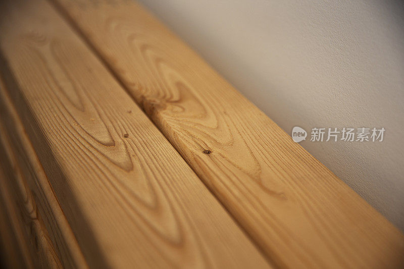 新鲜的木梁。堆放在墙边的木材。未经处理的木梁表面