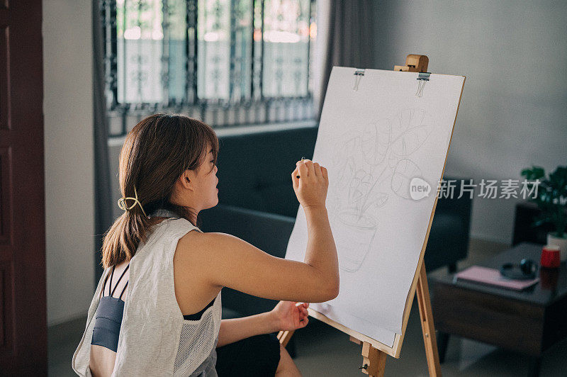 一个快乐的女人在家庭工作室的画架上画画