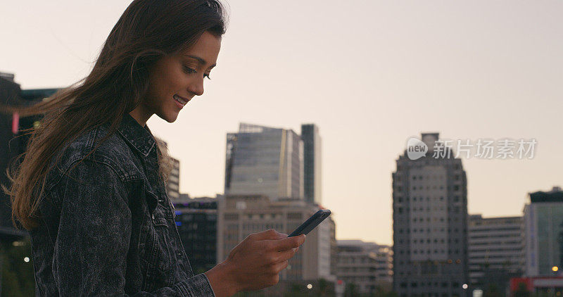 一个迷人的年轻女子站在城市外面发短信的镜头