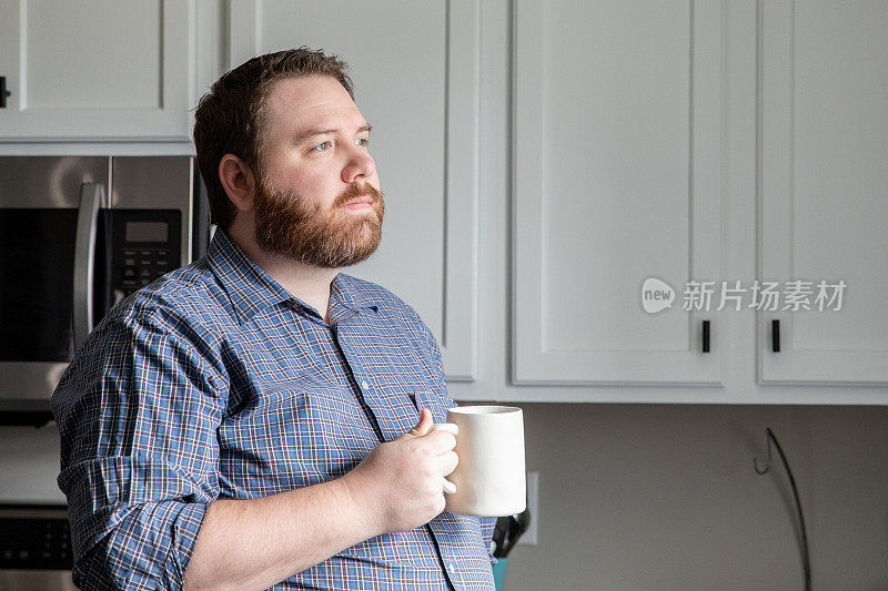 中年男人喝着咖啡凝视着厨房里的窗外
