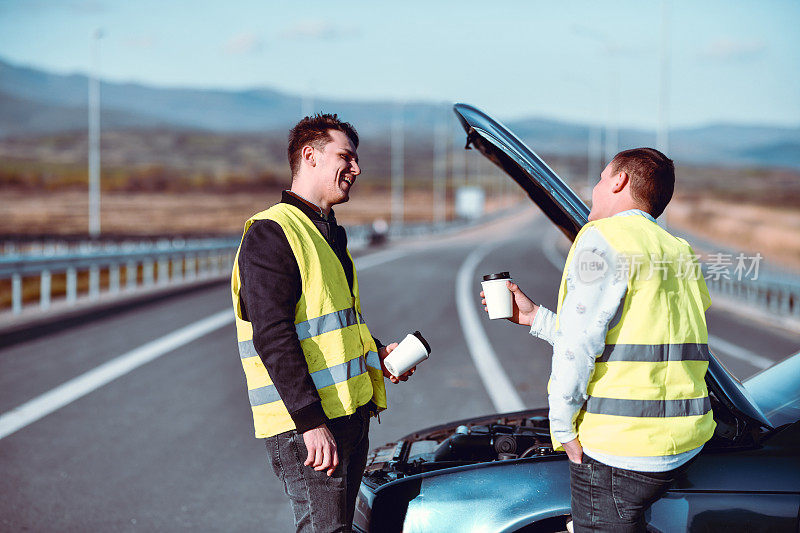 两个男人喝咖啡旁边抛锚的汽车，等待帮助