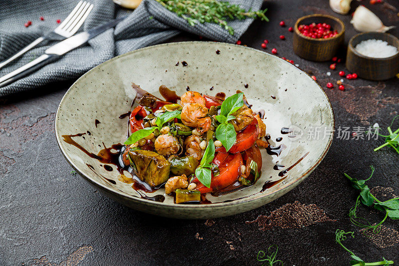 蔬菜、蘑菇、西红柿沙拉和炸虎虾放在深色的混凝土桌上