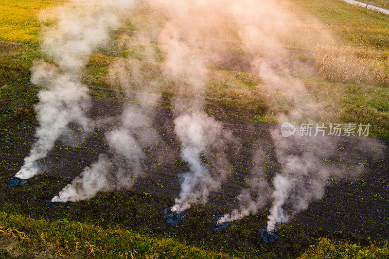 鸟瞰图的农业废物篝火，干草和秸秆秸秆燃烧的浓烟污染空气，在旱季的农田造成全球变暖和致癌烟雾