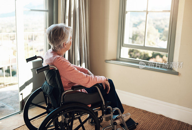 一位坐在轮椅上的老年妇女若有所思地看着窗外