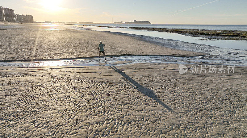 鸟瞰图，男子奔跑在空旷的海滩上