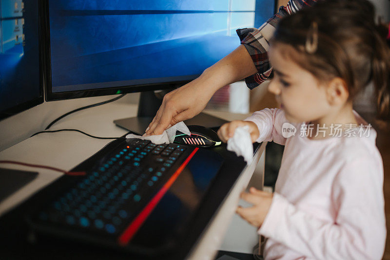 母亲和小女儿正在给电脑键盘消毒