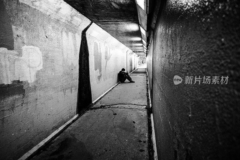 无家可归的人坐在寒冷黑暗的地铁隧道里
