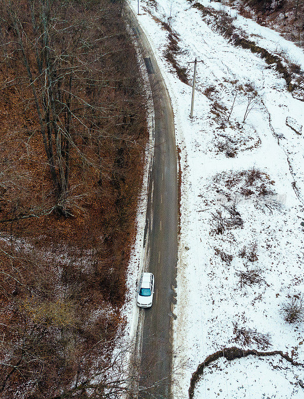 鸟瞰图的汽车行驶在乡村道路上通过雪天的冬季景观