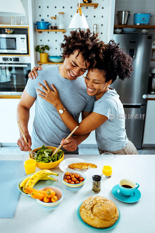 这是一对年轻夫妇在厨房里分享浪漫时刻的照片