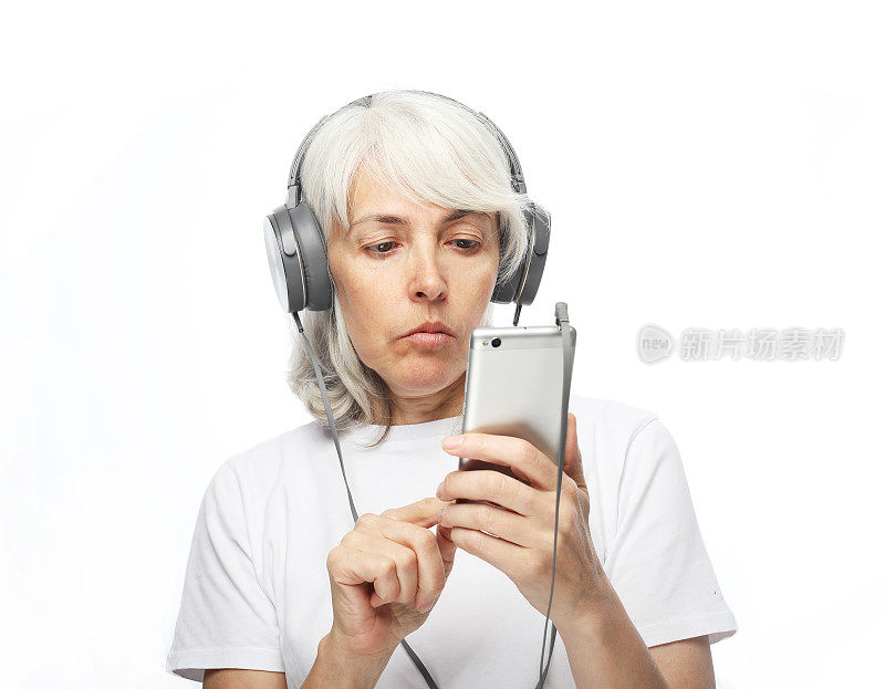 老妇人戴着耳机拿着手机滚动屏幕，选择歌曲。