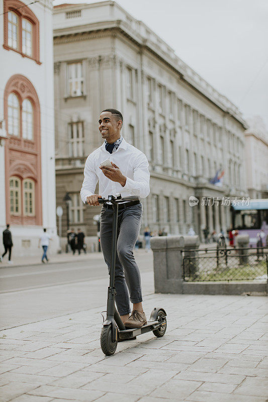 年轻的非洲裔美国人在街上骑着电动车玩手机
