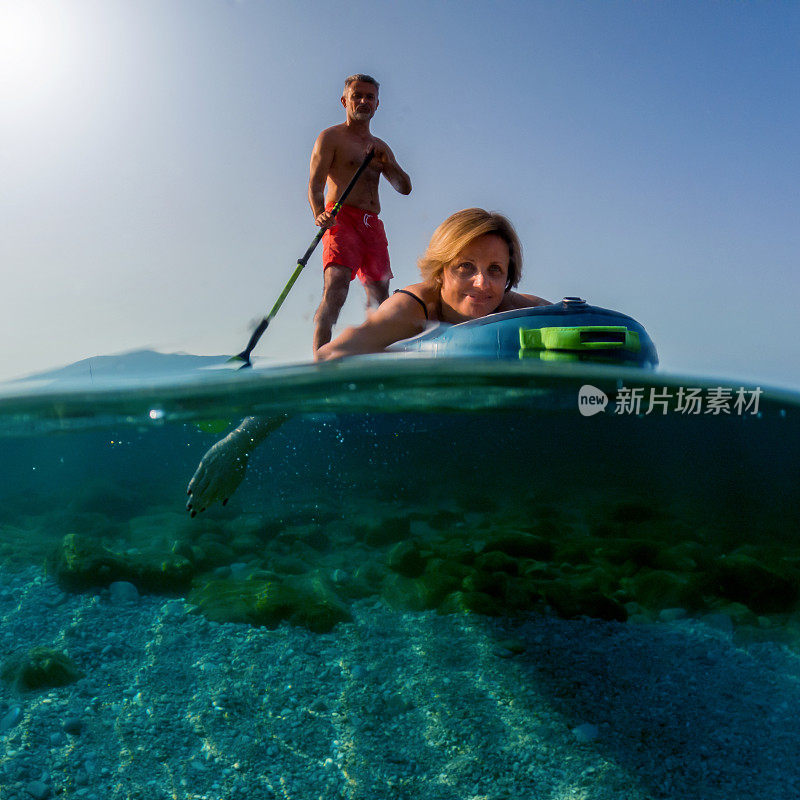 在一个阳光明媚的早晨，一对成熟的情侣在海滩上玩冲浪板。