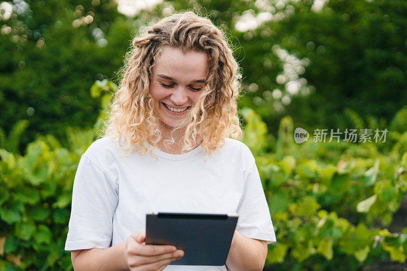 一位女农民正在检查葡萄园，并将数据从平板电脑上发送到云端。智慧农业和数字农业。互联网技术。质量控制。