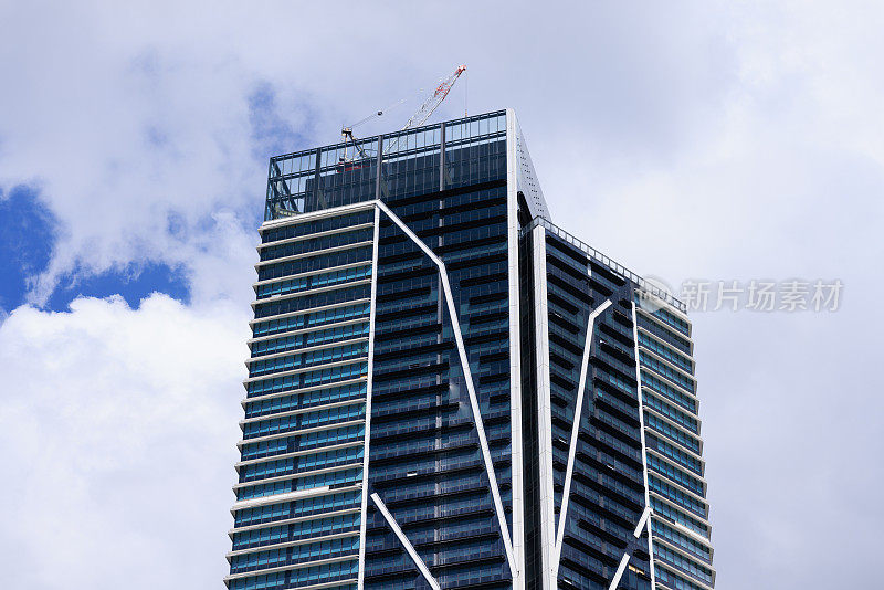 城市建筑的一部分，多云的天空和起重机在上面